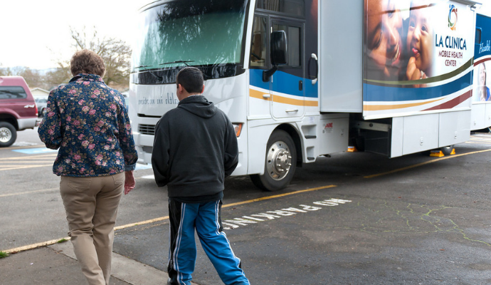 A nurse walks a student to his school’s parking lot for a checkup on the La Clinica Mobile Health Center. The center makes weekly stops at a number of community sites.